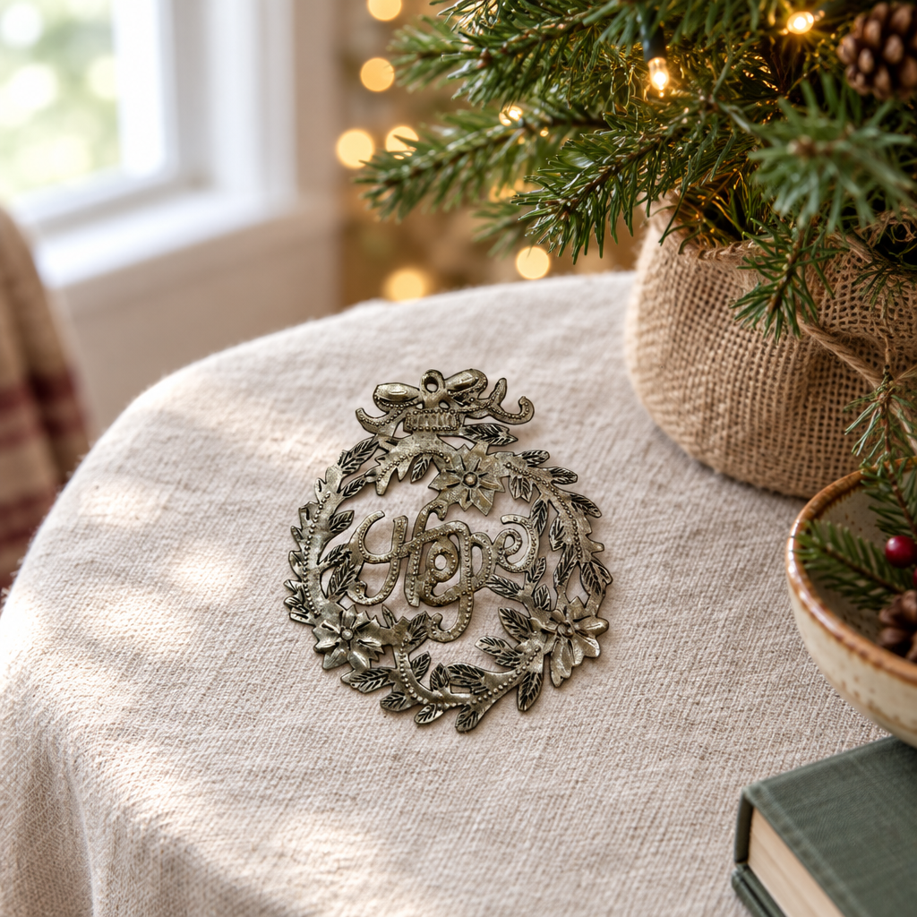 Handmade Haitian Hope metal Christmas ornament on a side table beside a Christmas tree
