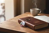 Maroon Inconnu keychain on travel journal at cafe – lifestyle photo