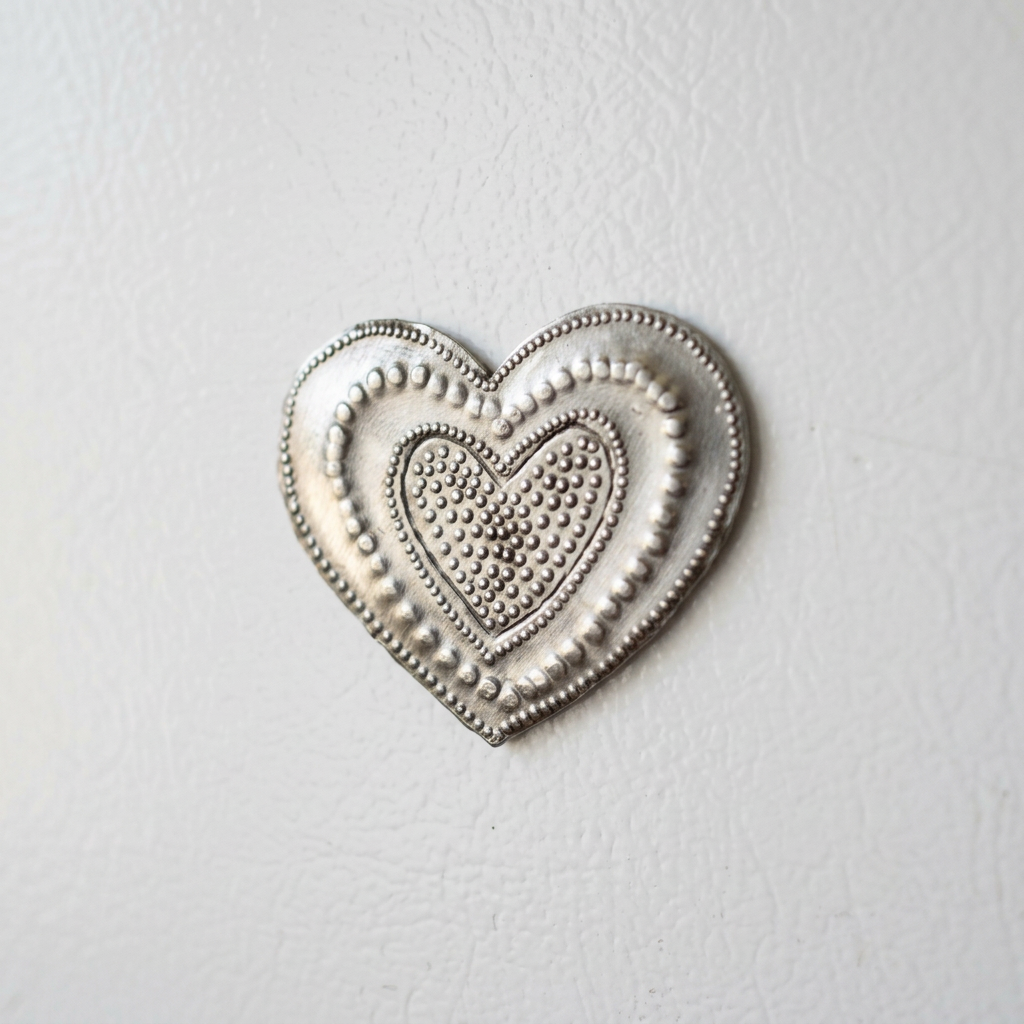 Close-up of the steel drum heart magnet’s nested-heart design and textured dotted borders
