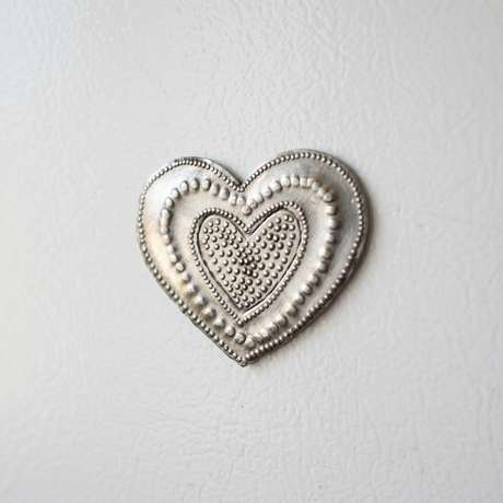 Close-up of the steel drum heart magnet’s nested-heart design and textured dotted borders