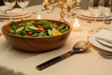 Haitian all-horn salad fork on luxury linen tablecloth beside wooden salad bowl by candlelight