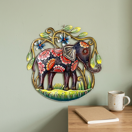Handmade Haitian steel drum elephant wall art beside a wooden office desk