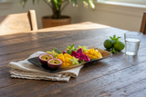 Haitian handmade ox horn serving tray styled on rustic wooden dining table with tropical fruits