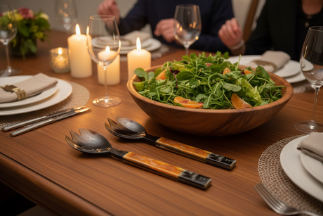 Haitian amber horn salad fork beside wooden salad bowl with citrus and greens at elegant candlelit dinner