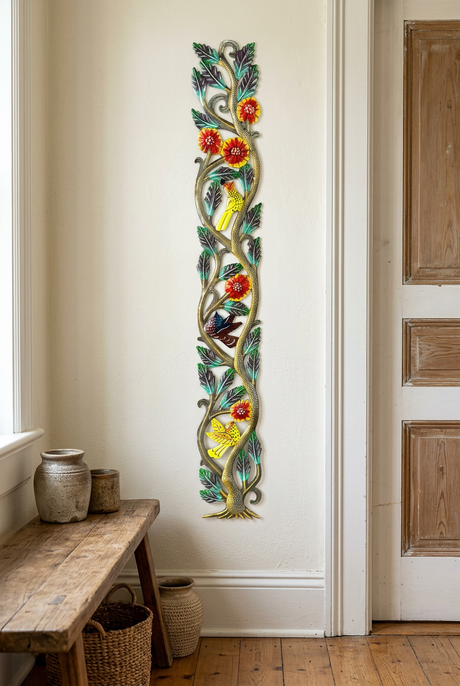 Tall narrow metal tree wall art with birds and flowers beside an entryway doorway.