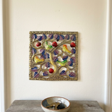 Small square Haitian bird metal wall art above an entryway console