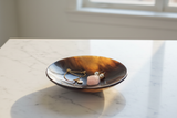 Haitian mahogany horn bowl holding gold bracelet and pearl earrings on white marble vanity