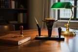 Haitian horn pen and inkwell stand on dark walnut writing desk with fountain pen journal and brass lamp