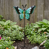 Turquoise and black butterfly garden stake near a wooden fence