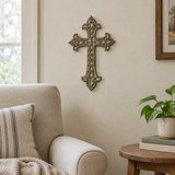 Ornate Haitian metal wall cross beside a living room armchair