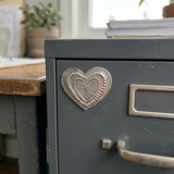 Small handmade metal heart magnet on a home office filing cabinet