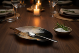 Haitian horn leaf spoon rest holding serving spoon beside salt bowl on dark walnut dining table