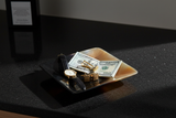Haitian black amber horn bowl as men's valet tray holding gold watch and cufflinks on granite
