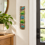 Handpainted Haitian stacked tropical fish metal wall art beside an entryway doorway