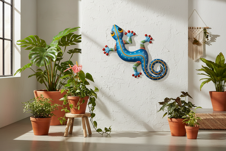 Haitian hand-painted blue metal gecko wall art mounted on white plaster wall with tropical plants