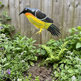 Yellow and black bird garden stake near a wooden fence