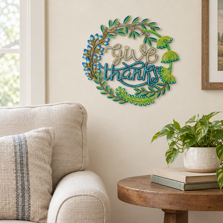Handpainted Haitian Give Thanks metal wall art beside a living room armchair