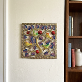 Haitian steel drum birds with red fruit wall art beside a bookshelf