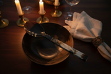 Haitian all-horn grand spoon as centerpiece beside horn bowl on dark walnut dining table by candlelight