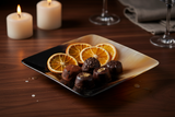 Haitian black amber horn bowl holding artisan chocolates on dark walnut surface by candlelight