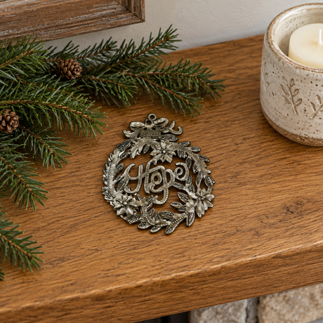 Handmade Haitian Hope metal Christmas ornament resting on a holiday mantel