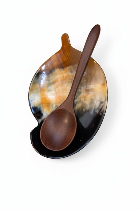 Handmade Haitian ox horn leaf-shaped spoon rest with amber and black pattern on white background