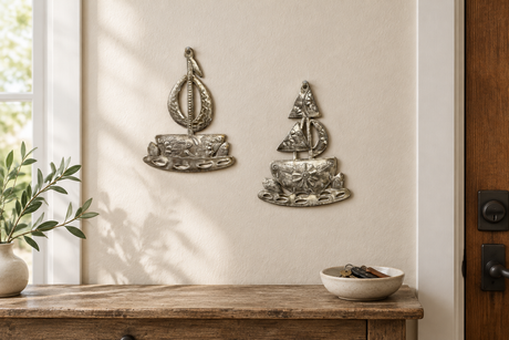 Two handcrafted metal sailboats displayed above an entryway console