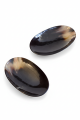 Handmade Haitian oval black ox horn dish with iridescent finish on white background