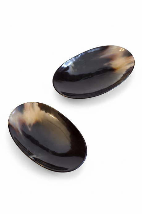 Handmade Haitian oval black ox horn dish with iridescent finish on white background