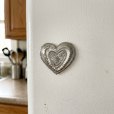 Handmade Haitian steel drum heart magnet on a white kitchen refrigerator