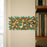 Small horizontal metal tree with green leaves beside a living room bookshelf