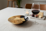 Haitian two-tone horn bowl as appetizer dish beside wine glass and crackers by candlelight