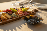 Haitian dark tortoiseshell horn bowl as condiment dish on luxury dining table beside charcuterie board