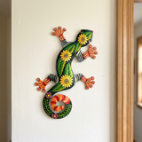 Sunflower lizard Haitian metal wall art beside a wood-trimmed doorway