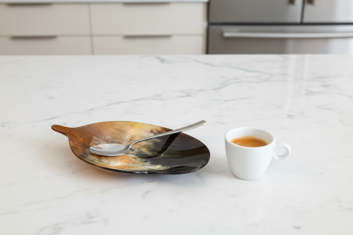 Haitian horn leaf spoon rest holding coffee spoon beside espresso cup on white marble counter