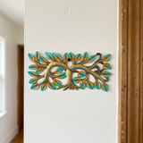 Horizontal Haitian metal tree wall art beside a wood-trimmed doorway