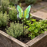Handcrafted green butterfly garden stake among herbs