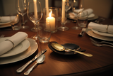 Haitian black horn leaf spoon rest holding gold serving spoon on dark walnut dining table by candlelight
