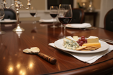 Haitian horn cheese knife on luxury dinner table beside cheese plate and wine glass by candlelight