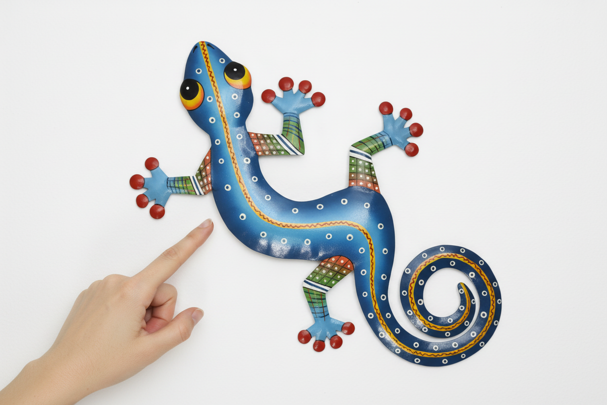 Haitian hand-painted metal gecko wall art shown next to a hand for scale, approximately 27 inches wide