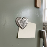 Recycled steel heart magnet holding a cream note card on a sage refrigerator