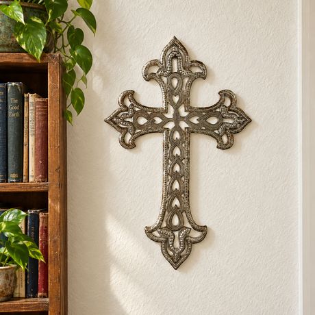 Ornate Haitian metal wall cross beside a hallway bookshelf