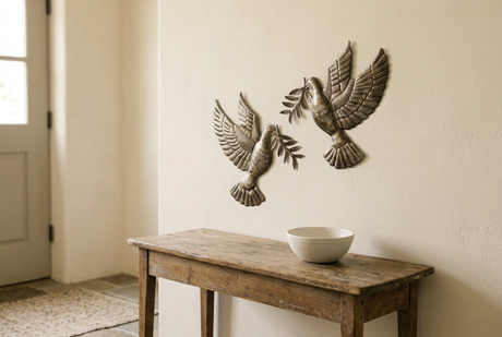 Two handmade Haitian metal doves with olive branches above an entryway console